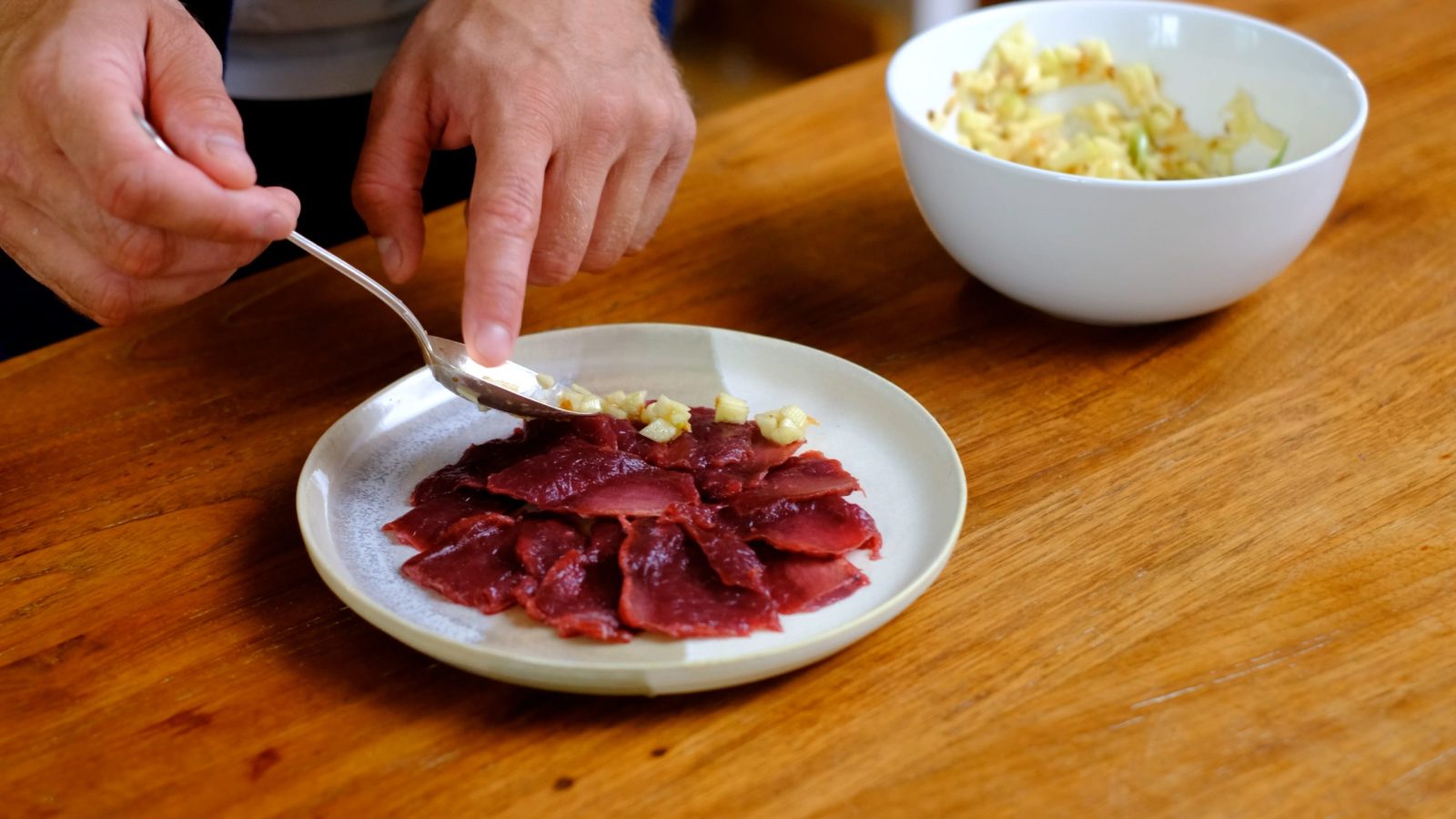 Dressage du carpaccio de cerf dans une assiette avec l'ail et les pommes