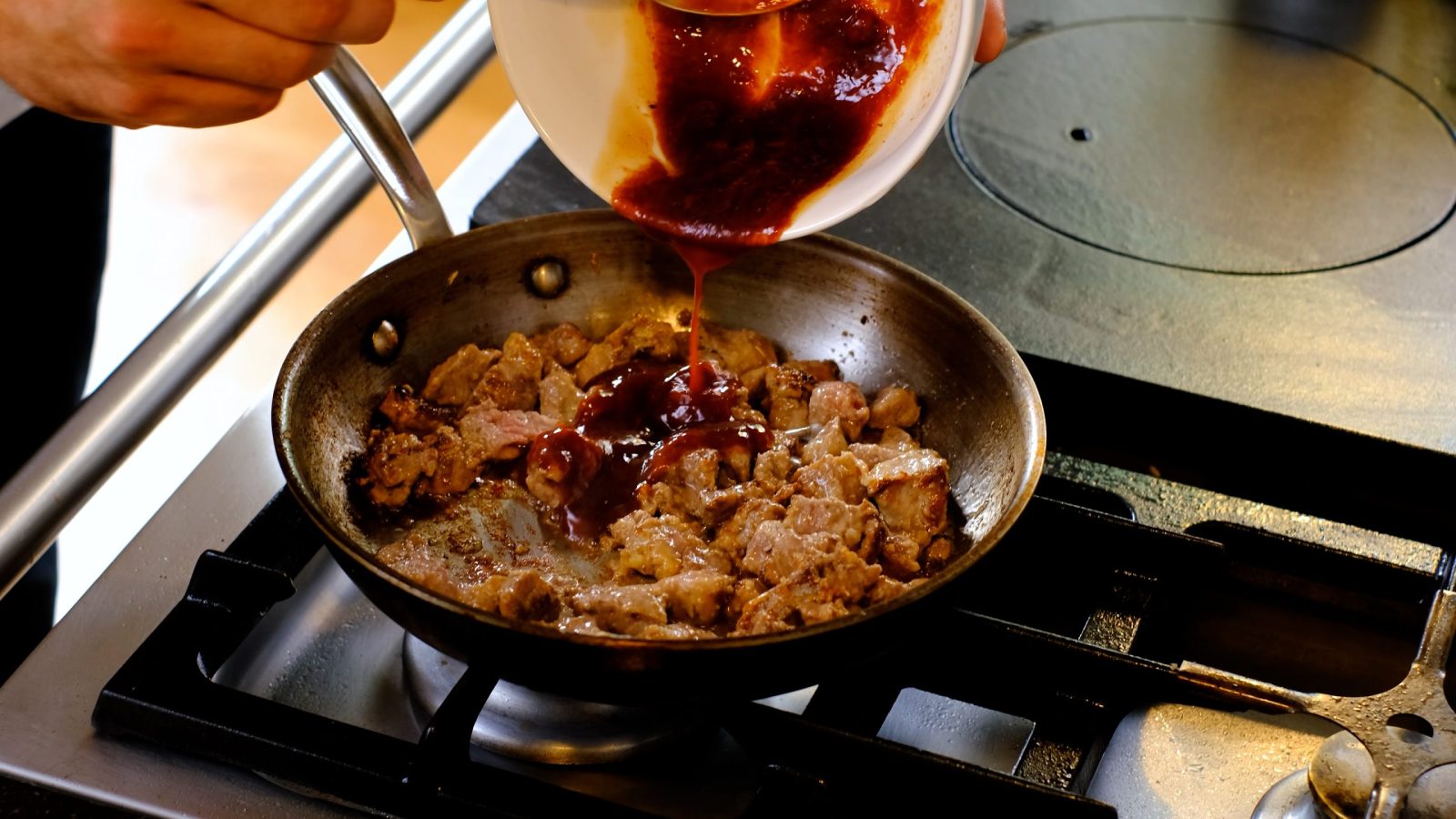 Ajout de la sauce au sauté de cerf dans la poêle pour cuisson