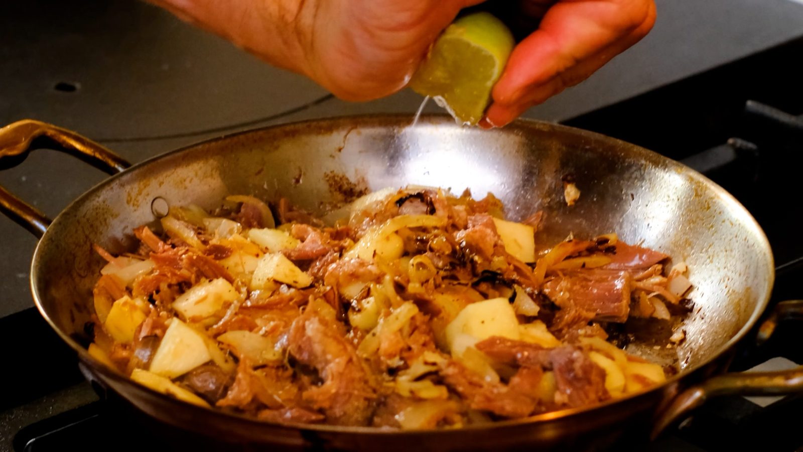 Cuisson du canard confit dans une poêle avec les pommes, l'oignon et l'ail